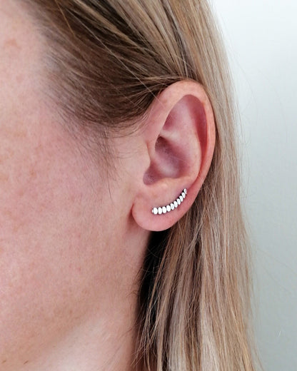 Close-up of a person wearing a small earring with a plain background