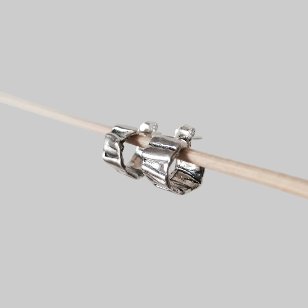 Silver knitting needle holder on a wooden knitting needle against a light gray background