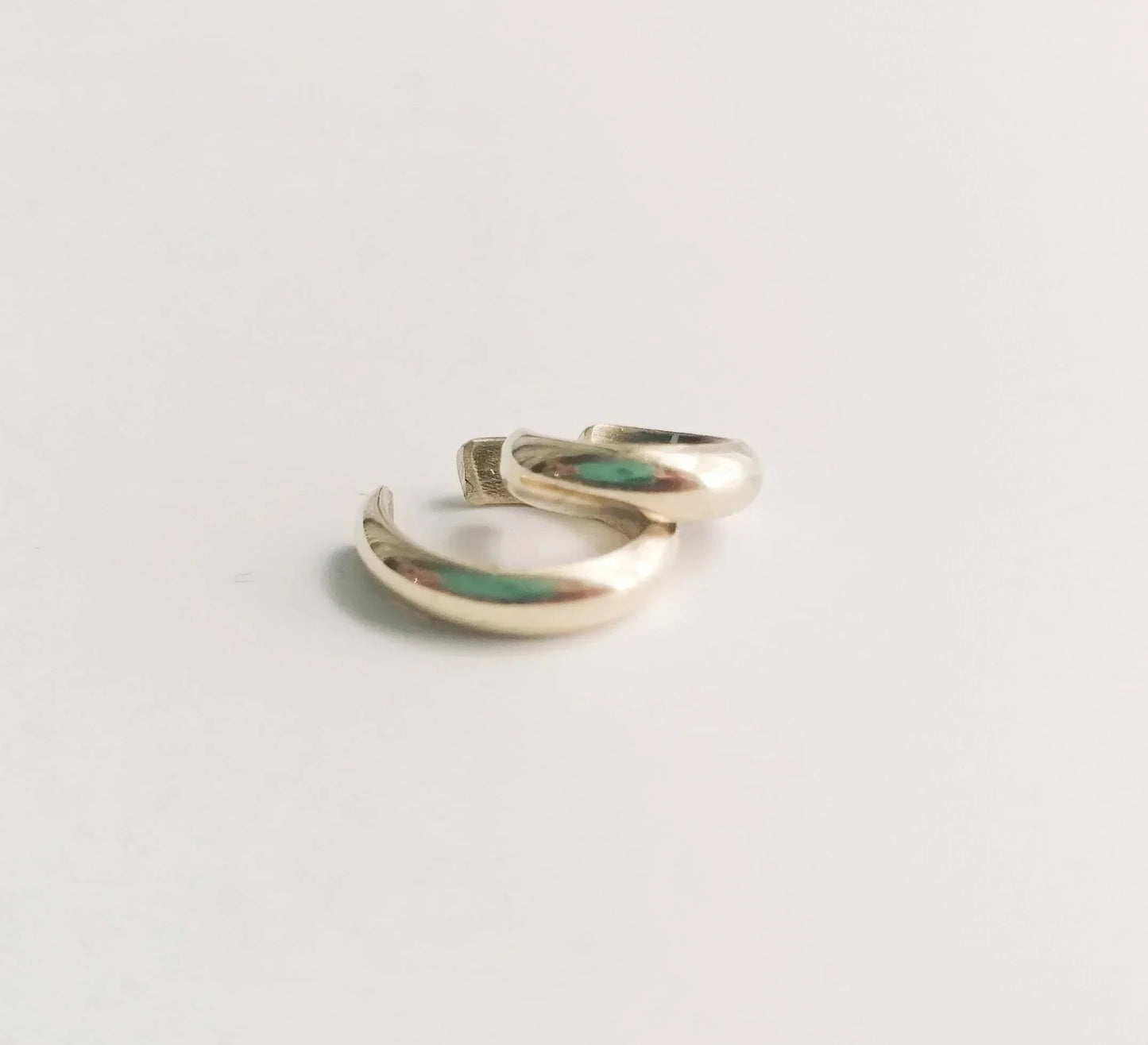 Minimalist gold hoop earrings on a white background