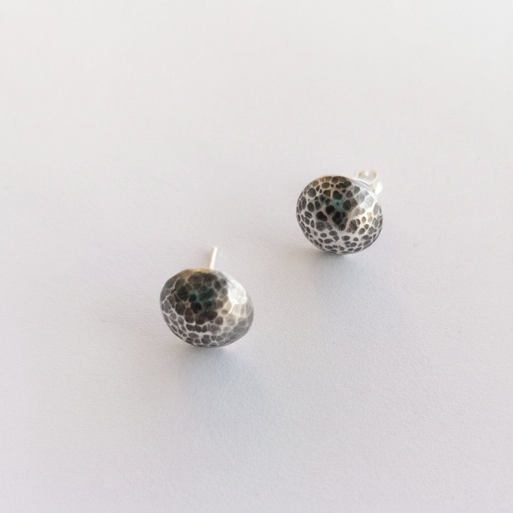 Pair of silver earrings with black speckled pattern on a white background