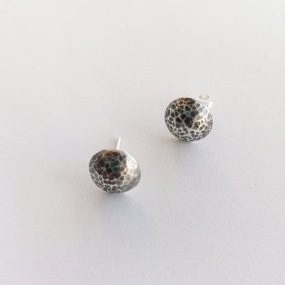 Pair of silver earrings with black speckled pattern on a white background