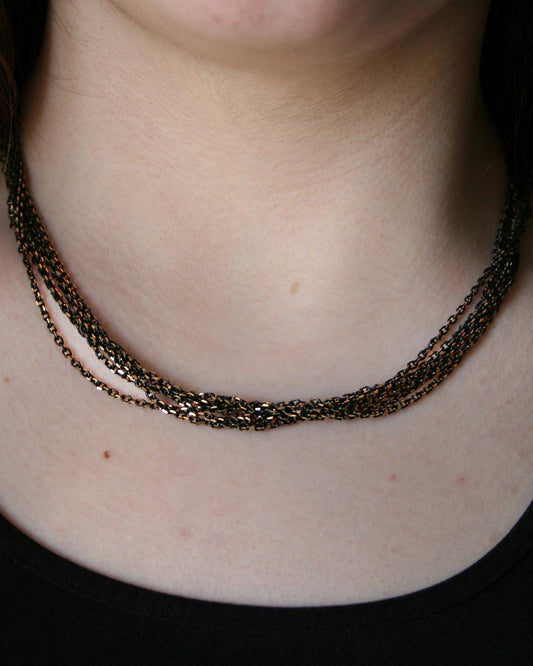 Close-up of a person wearing a layered necklace with a plain background