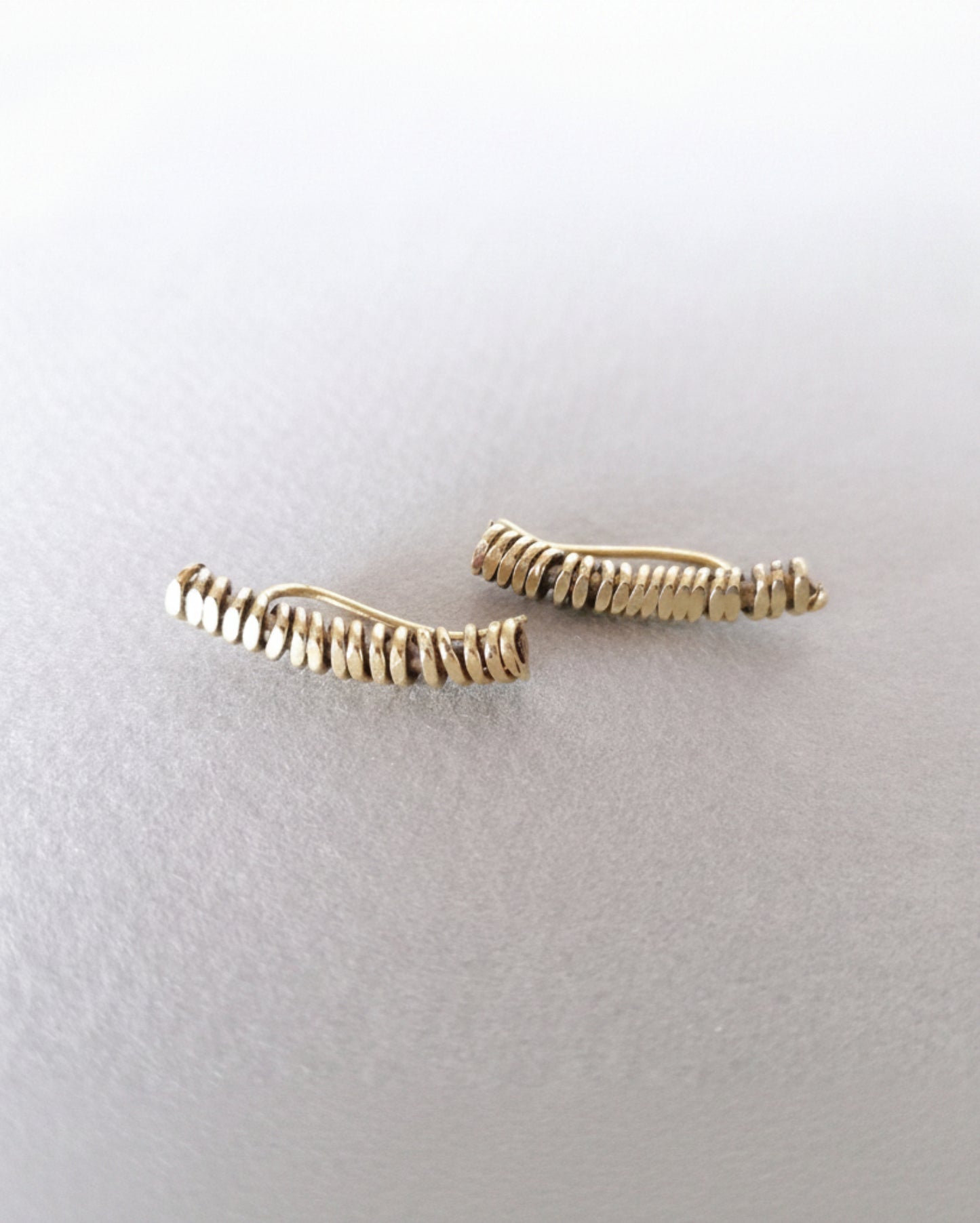 Two gold bar earrings on a light gray background