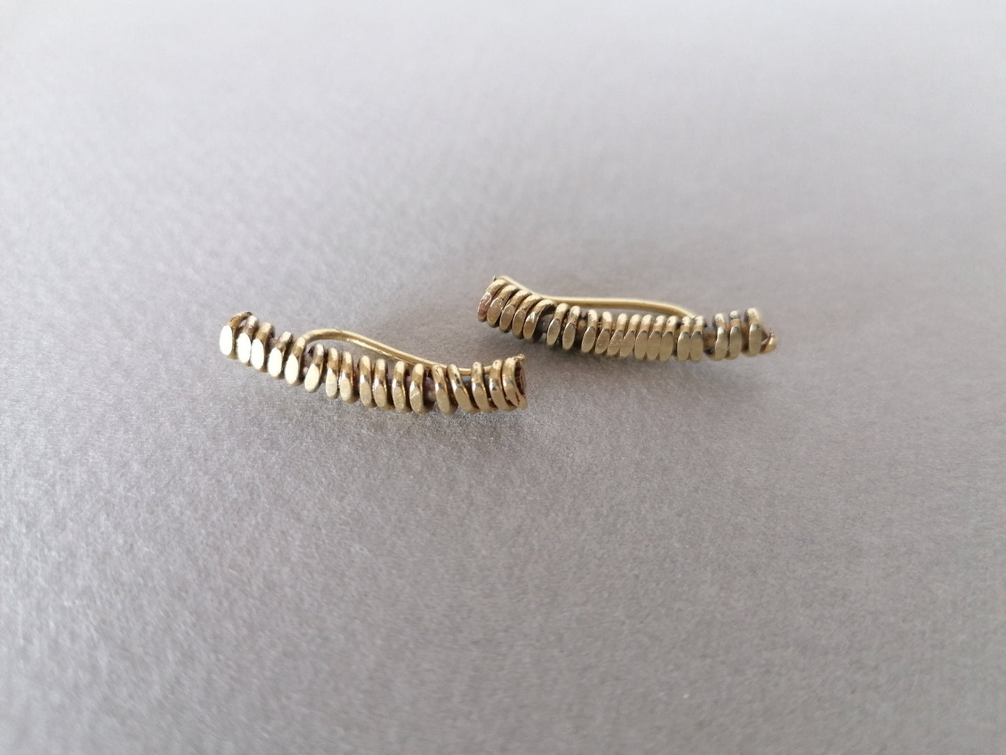 Two gold bar earrings on a light gray background