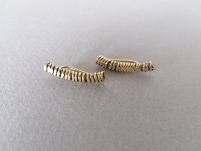 Two gold bar earrings on a light gray background