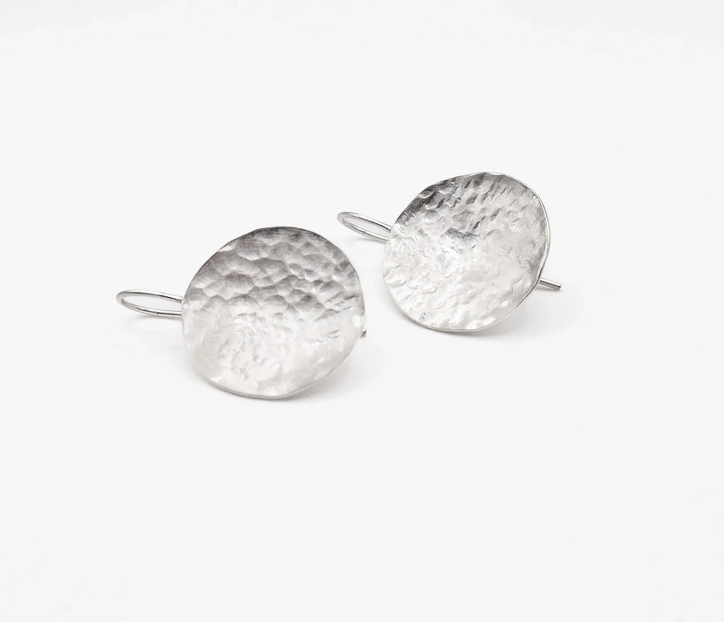 Handmade hammered silver disc drop earrings on white background