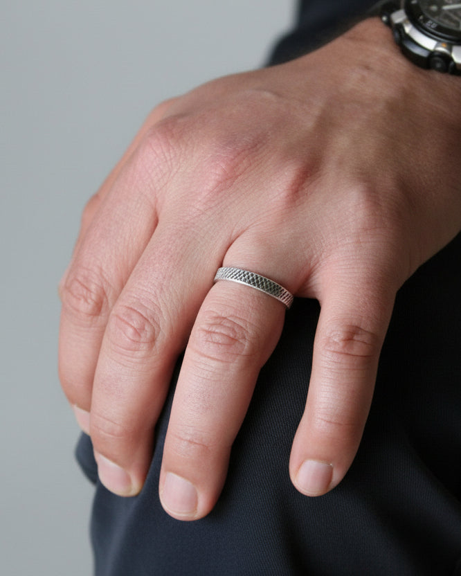 Hand wearing a silver ring with a blurred background