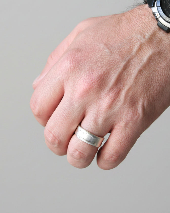 Hand wearing a silver ring with a blurred background
