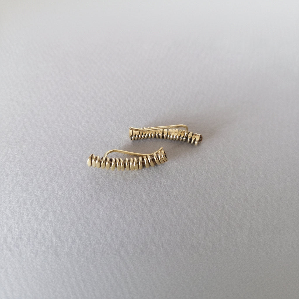 Pair of gold hair clips on a light gray background