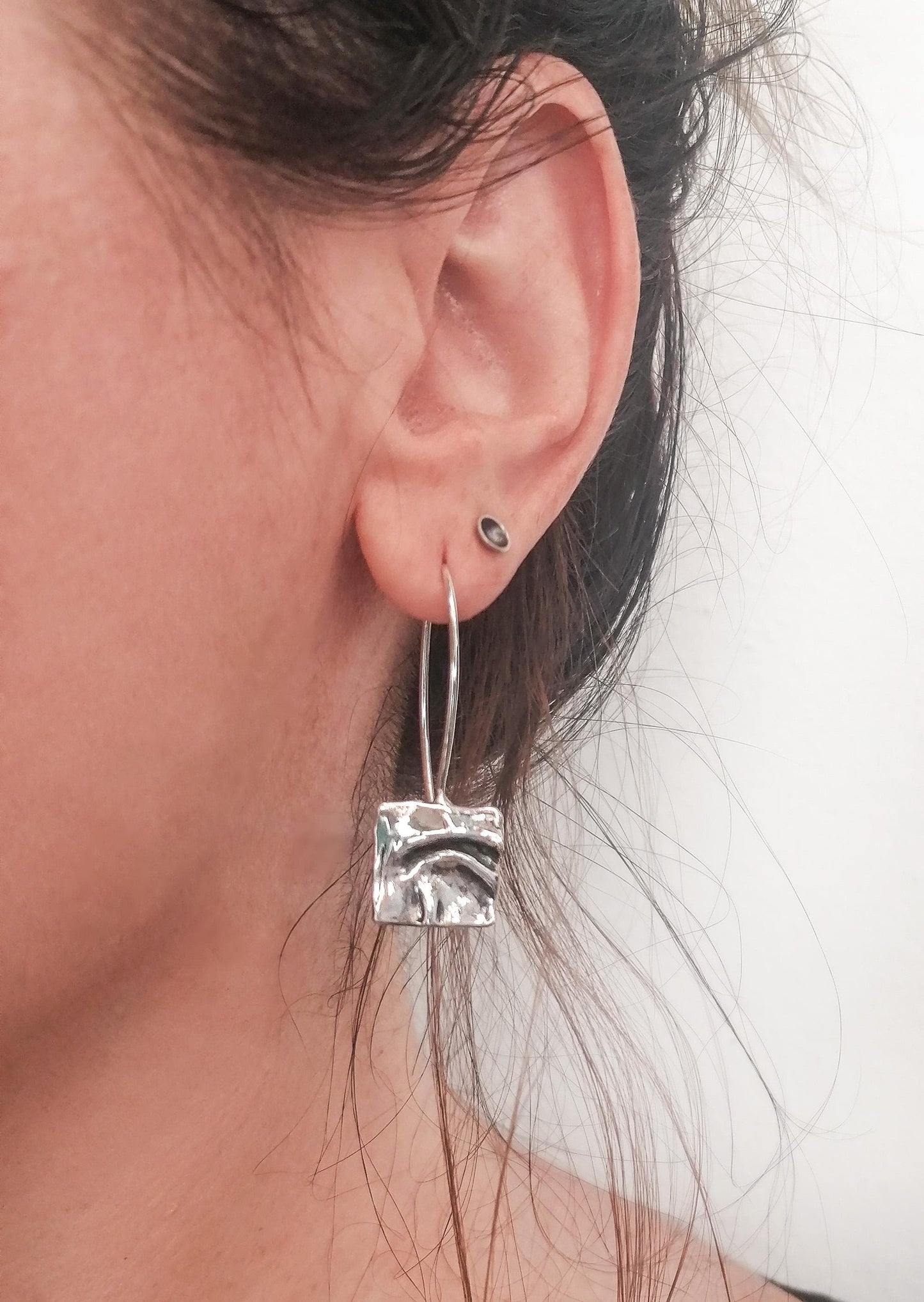 Woman wearing a modern silver square hammered hoop earring