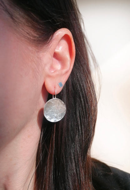 Woman wearing hammered silver round drop earring and geometric stud earring