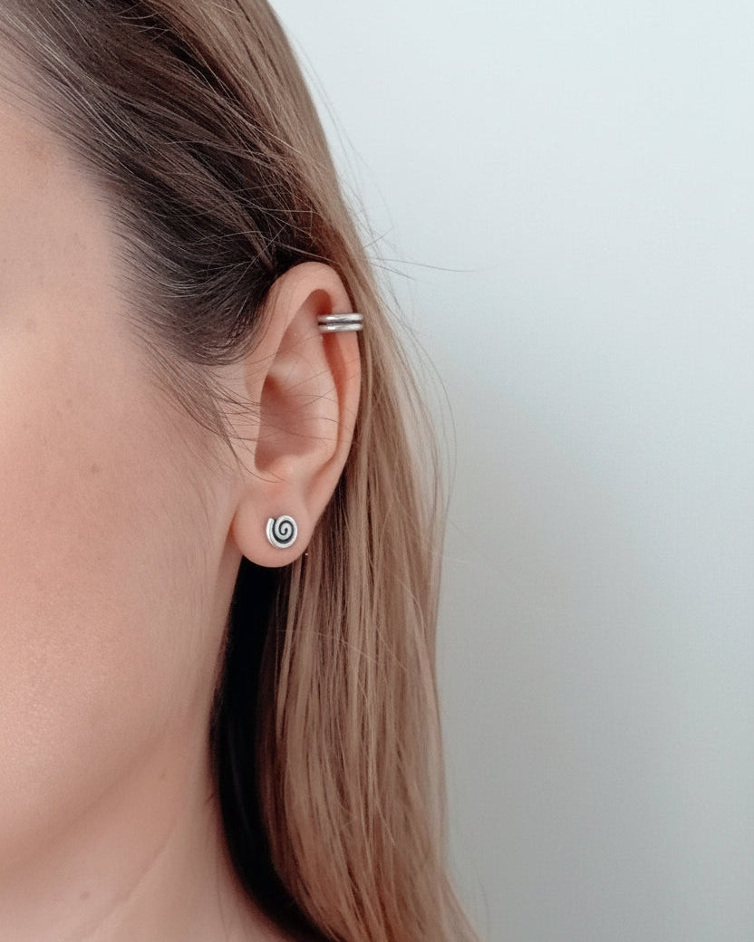 Close-up of a person wearing a silver hoop earring with a plain background
