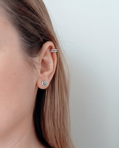 Close-up of a person wearing a silver hoop earring with a plain background