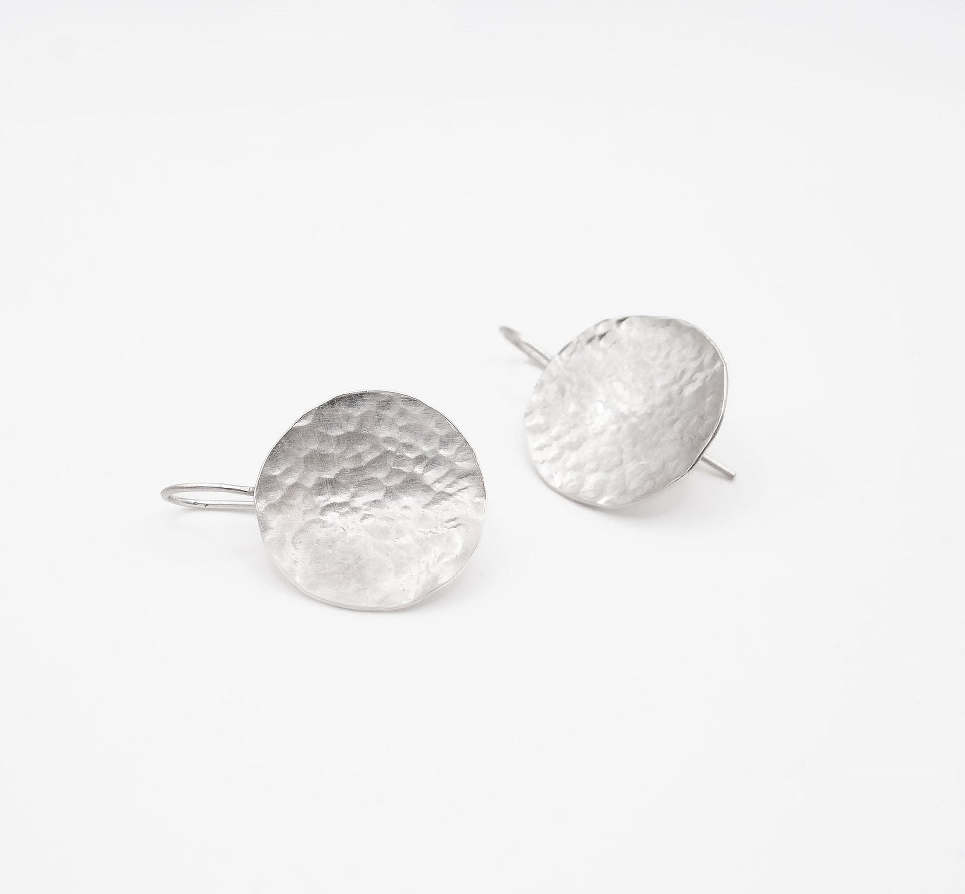 Handmade hammered silver disc earrings on white background