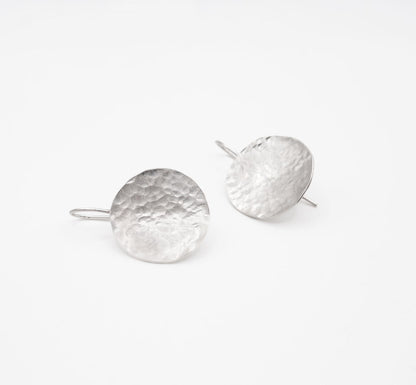 Handmade hammered silver disc earrings on white background