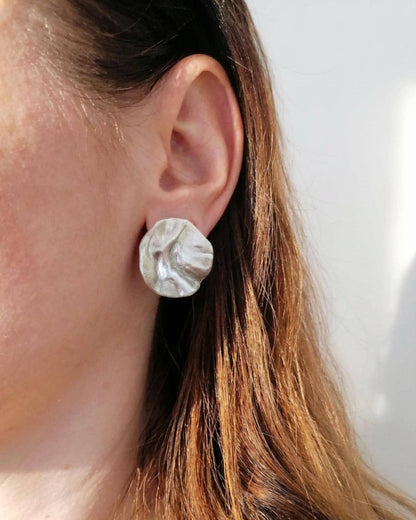 Close-up of an ear wearing a silver earring with a white background