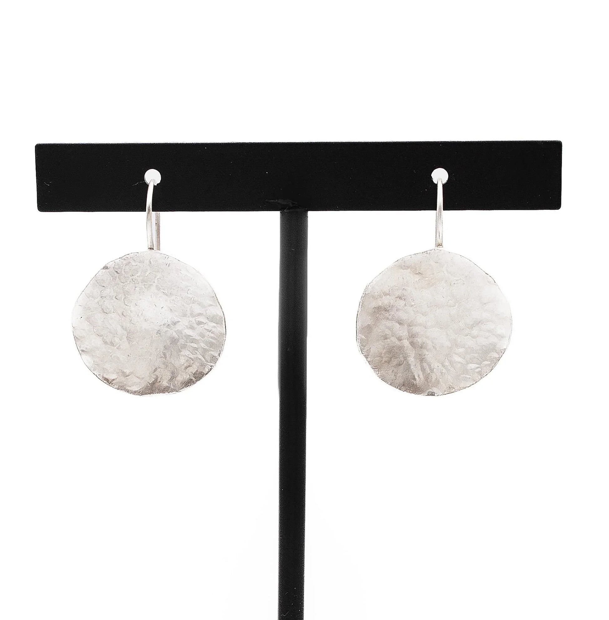 Handmade hammered silver disc earrings on a black jewelry stand