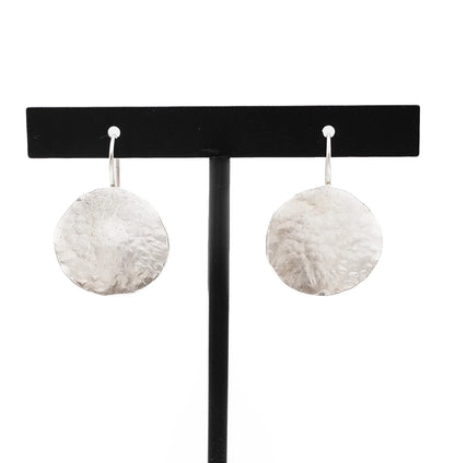 Handmade hammered silver disc earrings on a black jewelry stand