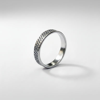 Silver ring with a textured pattern on a white background