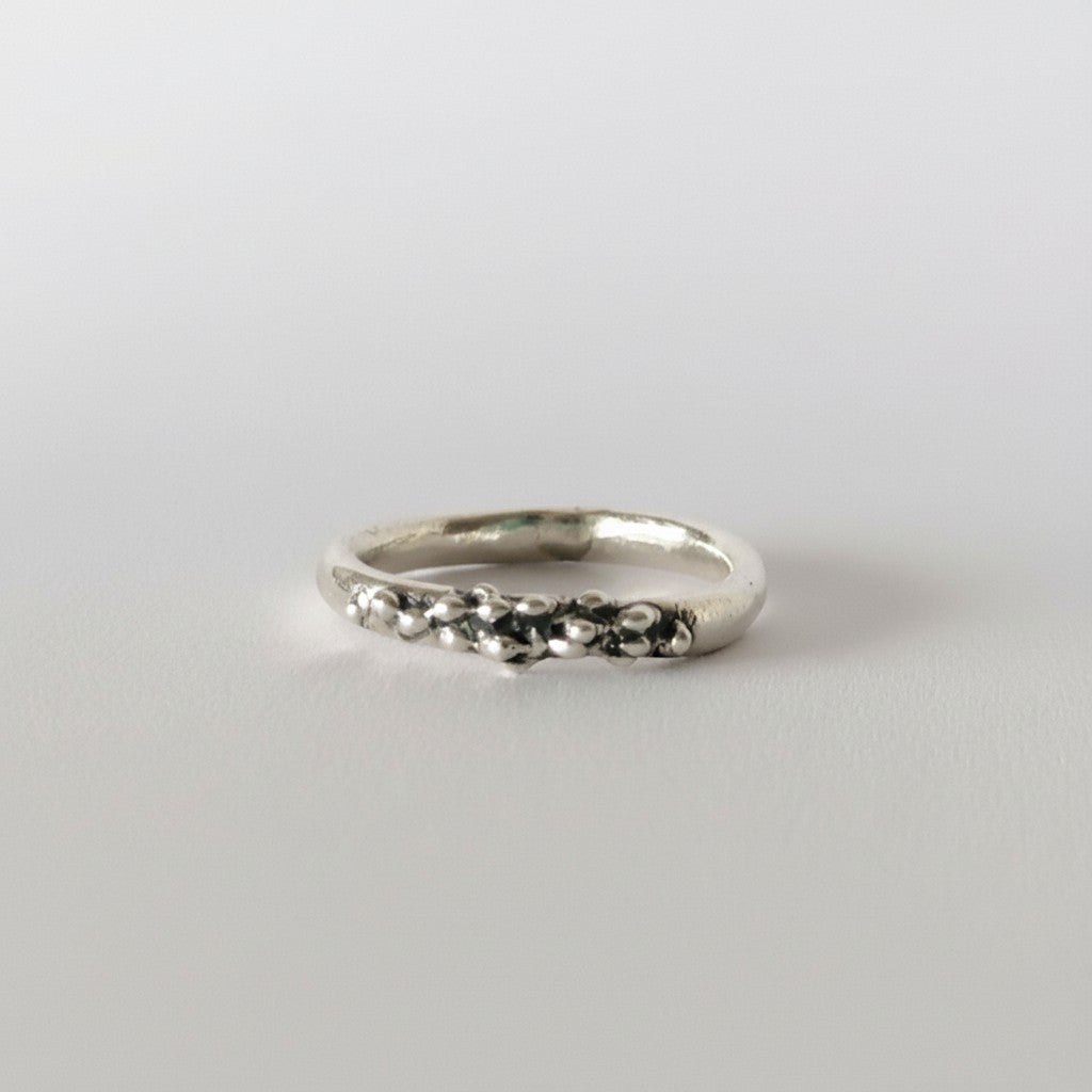 SosyGallery irregular sterling silver band ring with a sculptural, textured beaded design on a white background.