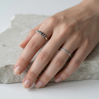 SosyGallery irregular sterling silver stacking rings with sculptural textured details worn on a hand over stone.