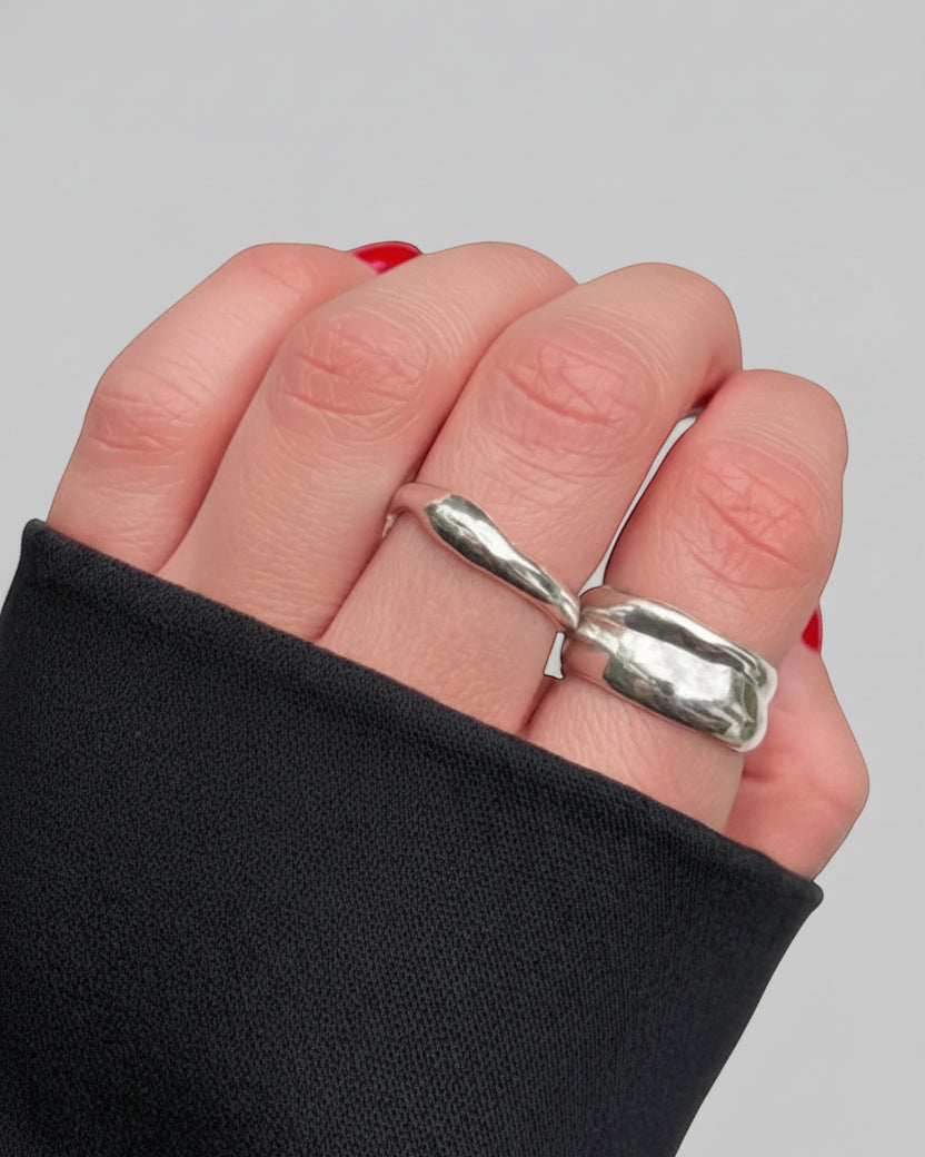 SosyGallery sterling silver organic shape rings with irregular, asymmetrical design worn on fingers with black sleeve.